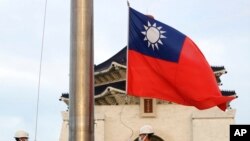 FILE - Two soldiers lower the national flag during the daily flag ceremony on Liberty Square of the Chiang Kai-shek Memorial Hall in Taipei, Taiwan, July 30, 2022. 