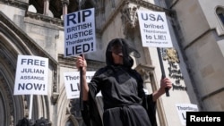 A person holds placards outside the High Court on the day of an extradition hearing of WikiLeaks founder Julian Assange, in London, May 20, 2024.