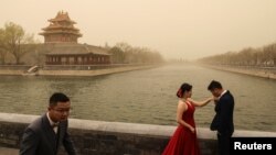 Foto pernikahan di dekat Kota Terlarang di Beijing, China, saat kota itu dilanda badai pasir, 15 Maret 2021. (REUTERS/Tingshu Wang)