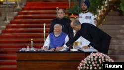 Perdana Menteri India Narendra Modi menandatangani dokumen setelah mengambil sumpahnya saat upacara pelantikan di istana presiden di New Delhi, India, 9 Juni 2024. (Foto: REUTERS/Adnan Abidi)