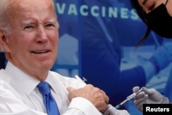 President Joe Biden receives an updated COVID-19 vaccine onstage in an auditorium on the White House campus in Washington, October 25, 2022.