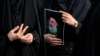 FILE - An Iranian woman holds a poster of the late President Ebrahim Raisi during a mourning ceremony for him at Vali-e-Asr square in downtown Tehran, Iran on May 20, 2024. 