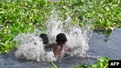 Children bathe in the Buriganga river on a hot summer day in Dhaka, Bangladesh, on April 19, 2023. 