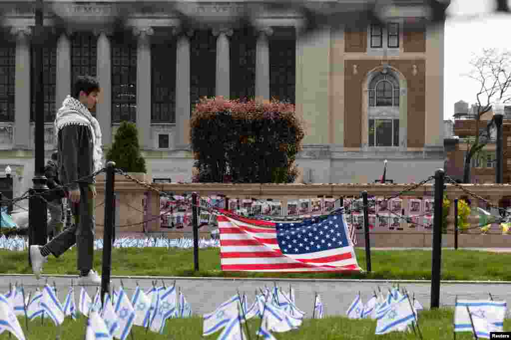 Un estudiante camina junto a banderas israelíes ubicadas cerca de un campamento de protesta en el campus principal de la Universidad de Columbia en apoyo de los palestinos.