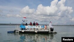 Pekerja mengoperasikan kapal pengumpul sampah bernama Mobula 8 di pelabuhan Benoa di Denpasar, Bali, 21 Maret 2023. (REUTERS/Johannes P. Christo)