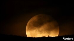 FILE - A full moon rises over Dajti Mountain in Tirana, Albania, March 25, 2024. 