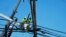 FILE - Linemen work on poles Aug. 13, 2023, in Lahaina, Hawaii, following a deadly wildfire that caused heavy damage days earlier. 