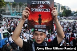 Seorang pria membawa plakat saat unjuk rasa pro-Palestina, di tengah konflik yang sedang berlangsung antara Israel dan Hamas, di Jakarta, 9 Juni 2024. (Foto: REUTERS/Ajeng Dinar Ulfiana)