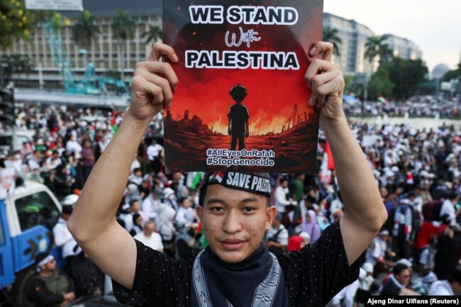Seorang pria membawa plakat saat unjuk rasa pro-Palestina, di tengah konflik yang sedang berlangsung antara Israel dan Hamas, di Jakarta, 9 Juni 2024. (Foto: REUTERS/Ajeng Dinar Ulfiana)