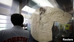 A man stands next to the blood stained shirt of a reporter who was bloodied by police in Tiananmen Square China during the uprising in 1989, at the Tiananmen June 4th Memorial museum in New York, June 1, 2023.