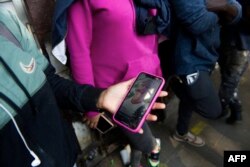 Seorang migran pengguna TikTok menyimak saran dari migran lain pada aplikasi tersebut, sebelum bergerak ke perbatasan AS di luar Komisi Bantuan Pengungsi Meksiko (COMAR) di Mexico City, 14 Maret 2023. (CLAUDIO CRUZ/AFP)