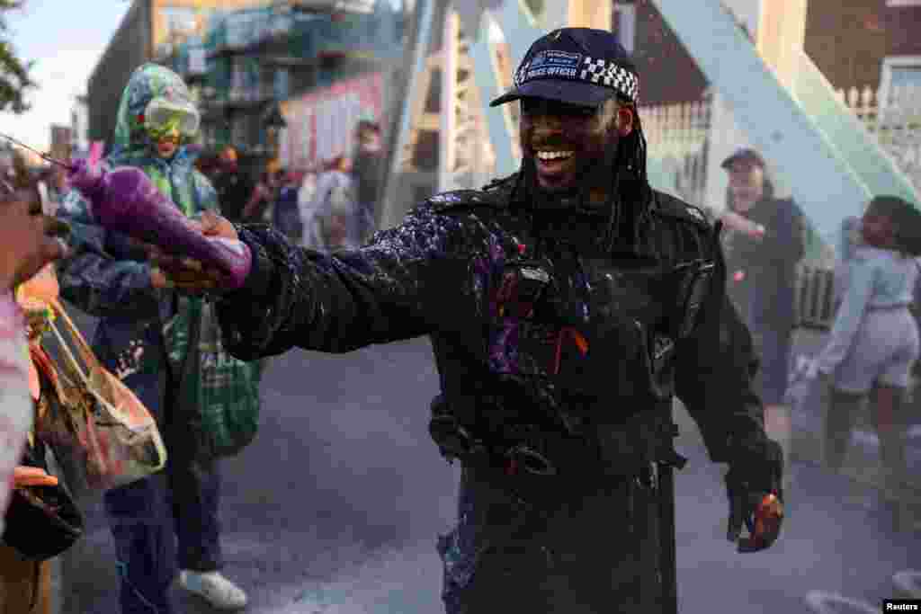 Полицаец прска со боја за време на прославите &bdquo;J&#39;Ouvert&ldquo; на изгрејсонце, за време на карневалот Нотинг Хил, во Лондон.