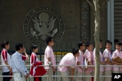 FILE - Chinese students wait outside the U.S. Embassy for their visa application interviews on May 2, 2012, in Beijing. (AP Photo/Alexander F. Yuan, File)