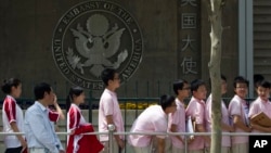 FILE - Chinese students wait outside the U.S. Embassy for their visa application interviews, May 2, 2012, in Beijing. 