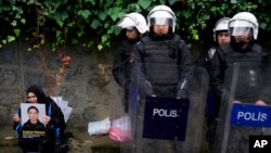 FILE - Turkish police stand next to a woman protesting China's crackdown on ethnic Uyghurs, at the Chinese Consulate in Istanbul, Nov. 30, 2022. Uyghur refugees in Turkey reportedly have been interrogated and detained in recent weeks. 