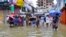 People carrying umbrellas, wade through a flooded street amid rainfall in Feni, Bangladesh, on Aug. 22, 2024.