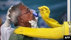 ঢাকায়, করোনভাইরাস পরীক্ষা করার জন্য একজন বাসিন্দার কাছ থেকে সোয়াব নমুনা সংগ্রহ করছেন, মুগদা মেডিকেল কলেজ ও হাসপাতালের একজন স্বাস্থ্য কর্মী। (ফাইল ছবি) 