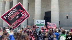 FILE - Students and parents rally at the Ohio Statehouse in support of possible changes that would increase eligibility for taxpayer-funded school vouchers to K-12 students statewide, May 17, 2023, in Columbus, Ohio. 