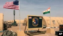 FILE - A U.S. and Niger flag are raised side by side at the base camp for air forces and other personnel supporting the construction of Niger Air Base 201 in Agadez, Niger, April 16, 2018.