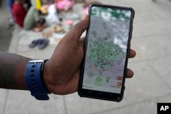 印度班加罗尔街头一名男子在手机上显示班加罗尔城的电动汽车充电桩。（2023年5月29日）