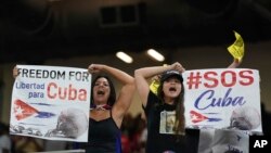 Los manifestantes sostienen carteles y cantan durante el juego del Clásico Mundial de Béisbol entre Cuba y Estados Unidos, el domingo 19 de marzo de 2023, en Miami. (Foto AP/Wilfredo Lee)