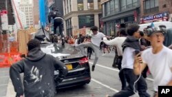 In this photo taken from video, people jump and kick a car as a crowd runs through the street on Broadway near Union Square, Aug. 4, 2023, in New York.