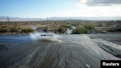 A driver forges Chino Creek, on State Highway 111, a major road leading in and out of Palm Springs, Calif., covered with moving water on Aug. 21, 2023, the morning after Tropical Storm Hilary passed through.