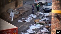 FILE - Medics stand by the covered bodies of victims of a deadly blaze in downtown Johannesburg, Aug. 31, 2023.