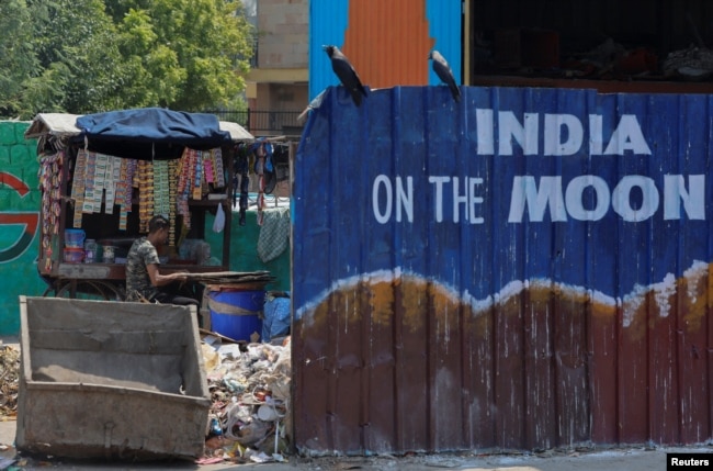 A roadside vendor waits for customers as he sits next to a mural ahead of G20 Summit, in New Delhi, Sept. 5, 2023.