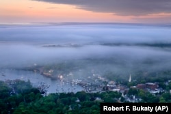 Layers of fog drift over in Camden, Maine, Tuesday, June 4, 2024. Many in the seaside community were outraged when they heard about a homeowner poisoning their neighbors trees for a view of the harbor on Penobscot Bay.(AP Photo/Robert F. Bukaty)