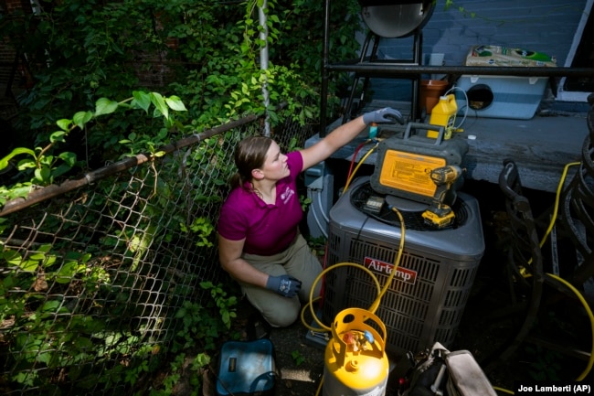 Jennifer Byrne, owner and technician at Comfy Heating and Cooling, works on an air conditioning condenser unit in Philadelphia on Thursday, Sept. 14, 2023. (AP Photo/Joe Lamberti)