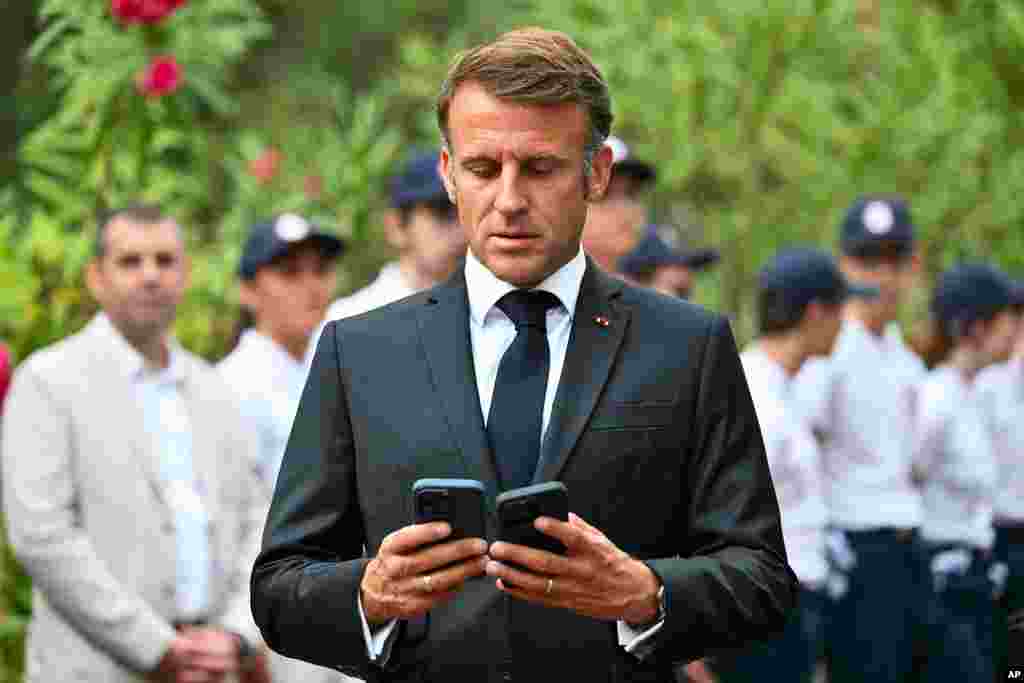 French President Emmanuel Macron looks at two smartphones during a ceremony marking the 80th anniversary of the Allied landings in Provence during World War II, at the Boulouris National Cemetery in Boulouris-sur-Mer, France.