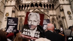 Manifestan kenbe pannkat apre Stella Assange, madanm fondate Wikileaks Julian Assange pibliye yon deklarasyon devan Kou Wayal Jistis la nan Lond, 26 Mas, 2024.