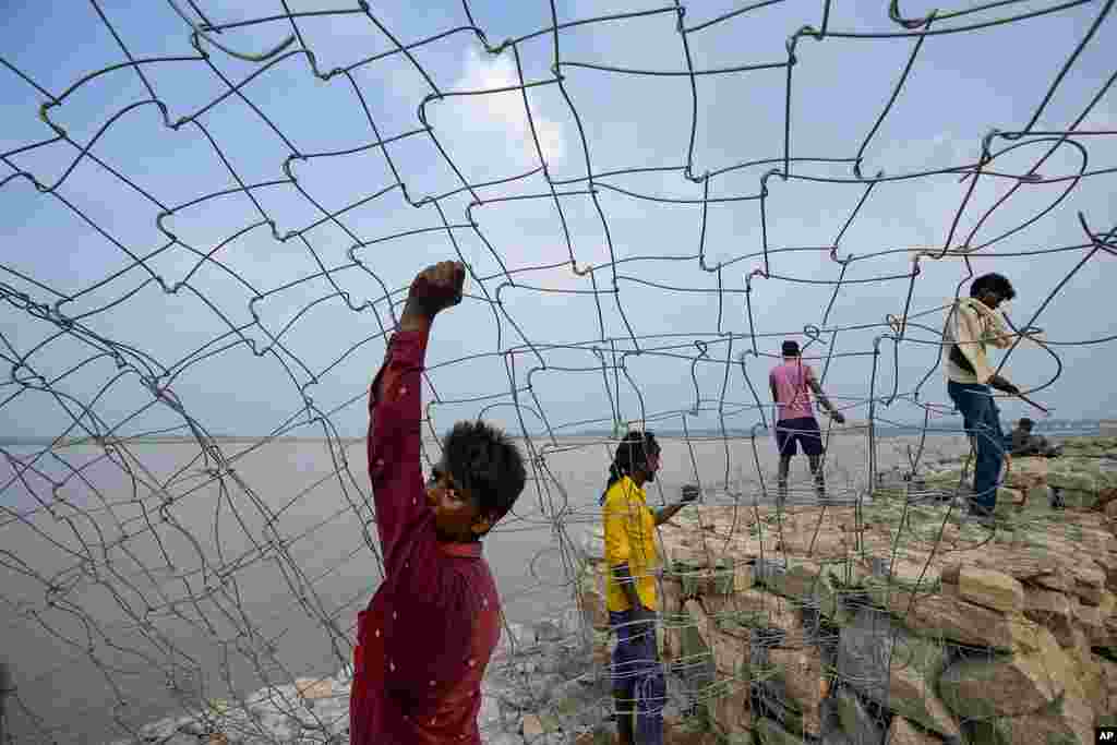 Para buruh India bekerja di lokasi pembangunan jalan yang berdekatan dengan Sungai Gangga dalam persiapan untuk festival Mahakumbh, di Prayagraj, negara bagian Uttar Pradesh, India utara. (AP)&nbsp;