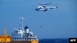 Helikopter penjaga pantai Jepang tampak mengangkat seorang perempuan, yang hanyut tersapu ombak ke semenanjung Boso di Chiba, dari kapal tanker yang menyelamatkan perempuan tersebut pada 10 Juli 2024. (Foto: Handout/Japan Coast Guard Yokosuka Office/AFP)