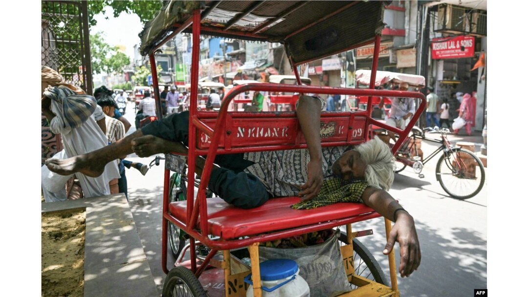 Seorang pria tertidur di atas rickshaw (sejenis becak) miliknya di pinggir sebuah jalan pada hari musim panas yang terik di New Delhi, India.