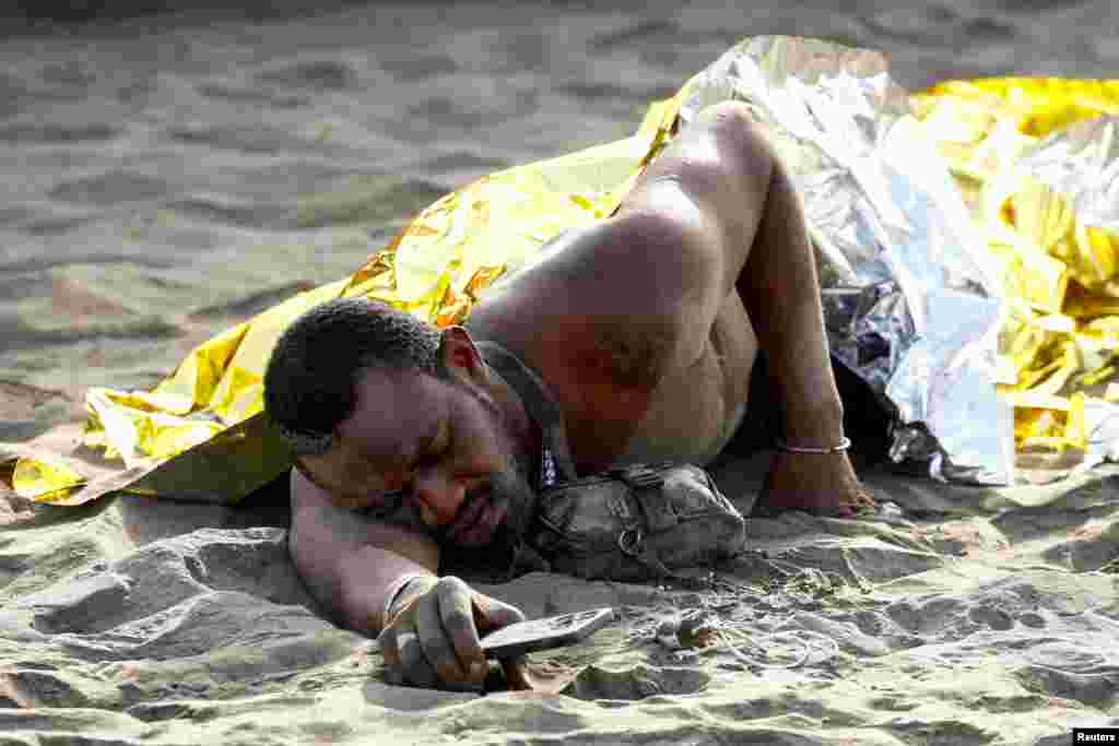 Seorang pria migran beristirahat di pasir setelah tiba dengan perahu karet di pantai Las Burras di San Agustin, di pulau Gran Canaria, Spanyol. (Reuters)&nbsp;