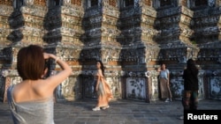 FILE - Tourists from mainland China dressed in traditional Thai costumes visit Wat Arun temple in Bangkok, Thailand, Jan. 18, 2023.