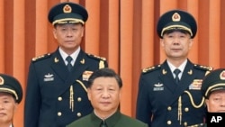 Chinese President Xi Jinping, center, poses for a photo with the new commander of China's rocket force Gen. Wang Houbin, top left, and its political commissar Gen. Xu Xisheng, top right, in Beijing, July 31, 2023. (Li Gang/Xinhua via AP)