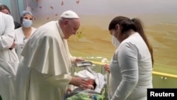 Pope Francis baptizes a baby boy as he visits the children's cancer ward at Gemelli Hospital where he was admitted for a respiratory infection, in this screengrab taken from a video, in Rome, Italy, March 31, 2023. (Vatican Media/Handout via Reuters)