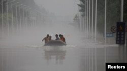 中国河北涿州民众在滔滔洪水中乘坐橡皮艇逃生。（2023年8月3日）