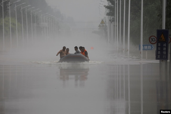 中国河北涿州民众在滔滔洪水中乘坐橡皮艇逃生。（2023年8月3日）