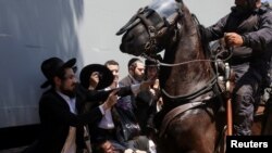 A protester clashes with an Israeli police officer on a horse during a demonstration against military conscription at Tel HaShomer recruitment base, in Ramat Gan.