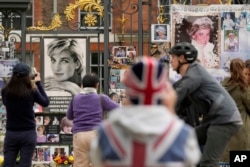 Orang-orang berdiri di depan foto Putri Diana di gerbang Istana Kensington di London, 31 Agustus 2023. (Foto: AP)