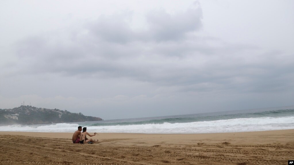 ARCHIVO - Turistas sentados en la playa de Acapulco, México, el martes 24 de octubre de 2023.