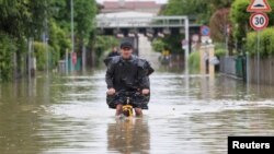 Seorang pria mengendarai sepeda melewati jalanan yang tergenang banjir setelah hujan lebat melanda wilayah Emilia Romagna, di kota Lugo, Italia. 