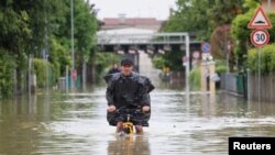 A man rides on a bicycle through floodwaters after heavy rains hit Italy's Emilia-Romagna region, in Lugo, Italy, May 19, 2023. 