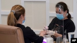 FILE - A nail technician gives a manicure to a customer at KB Nails in Sacramento, California, on Jan. 25, 2021. 