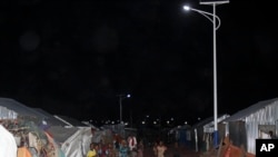 FILE - Children play under the solar powered street lights at a refugee camp in Mogadishu, July 11, 2013.