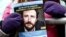 FILE - A demonstrator holds a flier with a photo of detained Belgian aid worker Olivier Vandecasteele, at a rally organized by Amnesty International and a support committee to ask for his liberation, in Brussels, Jan. 22, 2023.